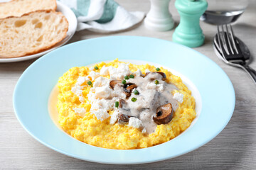 Tasty banosh served with brynza and mushrooms on light wooden table, closeup. Traditional Ukrainian dish