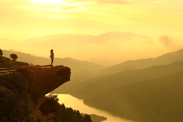 Woman breathing in the top of a cliff at sunrise in the mountain