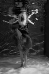 Naklejka na ściany i meble Black and white photographs where a beautiful girl poses in the water. She looks like a mythical mermaid