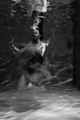 Fototapeta na wymiar Black and white photographs where a beautiful girl poses in the water. She looks like a mythical mermaid