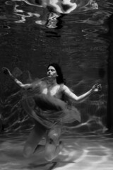 Black and white photographs where a beautiful girl poses in the water. She looks like a mythical mermaid