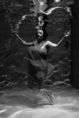 Fototapeta na wymiar Black and white photographs where a beautiful girl poses in the water. She looks like a mythical mermaid