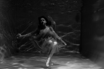 Black and white photographs where a beautiful girl poses in the water. She looks like a mythical mermaid