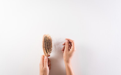 Healthcare problem concept. Woman hand holding hair loss or hair fall in comb on white background.