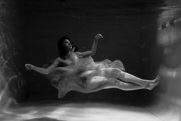 Obraz na płótnie Canvas Black and white photographs where a beautiful girl poses in the water. She looks like a mythical mermaid