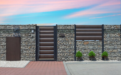 Modern wicket integrated with gabions wall. Fence made of gabions. Closed metal gate to property,...