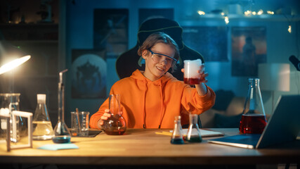 Smart Young Boy in Safety Glasses Mixes Chemicals in Beakers at Home. Teenager Conducting...