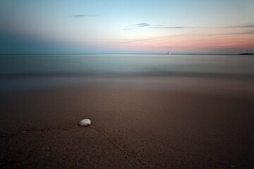 High angle shot of a sandy beach and tranquil seascape merged with skyline at sunrise