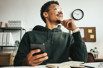 Investing in stock exchange market. Smiling black casual man working using mobile phone app