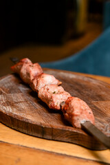 Shashlik or Shish kebab, Shashlyk skewered meat on a wooden board in restaurant. Blurred background.
