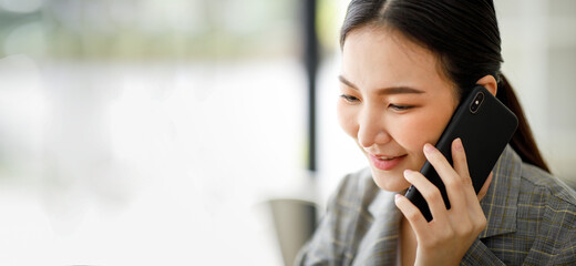 Asian young Businesswoman talking on cell phone in office hallway,blur background.