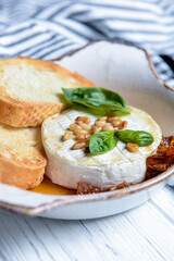 Baked camembert with sauce and toast served in a white bowl. Delicious dinner idea
