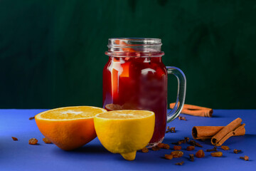 Homemade honey, cinammon and lemon tea in mason jar over blue background.