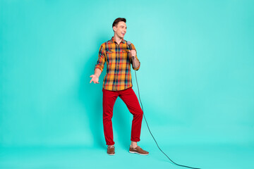 Full length photo of funny brunet millennial guy talk in mic wear shirt trousers sneakers isolated on teal background