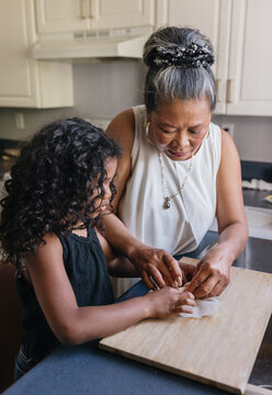 Grandmother making spring rolls with grandchild