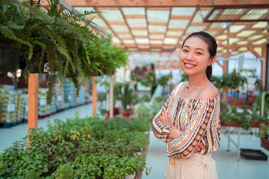 Cheerful ethnic buyer with crossed arms in garden shop