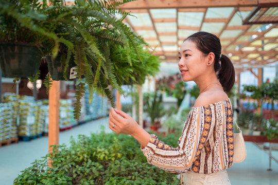 Asian shopper in disposable mask picking fern in garden shop