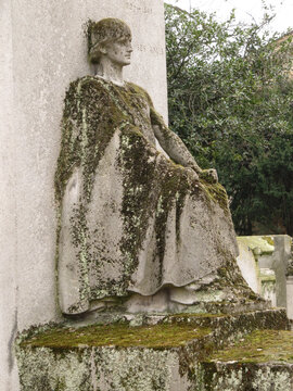 Sad sitted sculpture of a woman looking at the horizon in a tomb in the Pere Lachaise cemetery. All Saints Day, November 1, Day of the Dead, Dia de muertos.