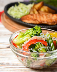 Sauteed vegetable salad with broccoli, asparagus, sweet pepper and cellophane noodles or fensi noodles in a glass bowl