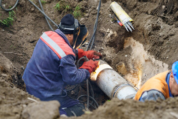 Plumber standing in pit is engaged in elimination of communal accident outdoors. Utility worker...