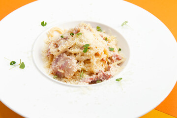 Corbanara pasta with bacon. In a plate on a colored background.