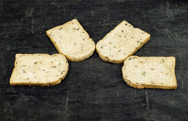 Whole wheat bread slices have rice grain isolated black wood background.