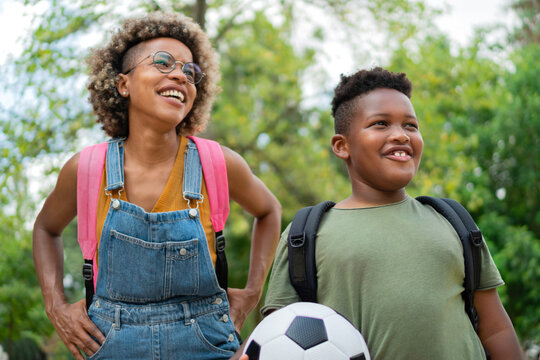 Happy black mother and child after a day at school. Joyful beautiful Mum and cute kid at the park smiling. Family happiness. Young Motherhood.