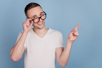Photo of young man happy positive smile point finger empty space ad advice select suggest isolated over blue color background