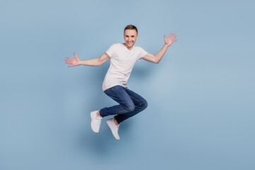 Full body profile side photo of cheerful excited man jumping have fun isolated over blue color background