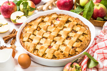 Apple pie. Traditional apple cake with ingredients for cooking at white wooden table.