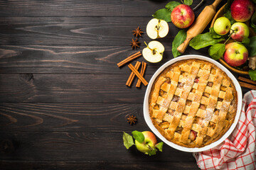 Apple pie with ginger and cinnamon at dark wooden table. Traditional autumn baking. Top view image with copy space.