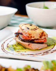 Rosemary chicken with oven-roasted ratatouille served on a white square plate over table with green plaid tablecloth.