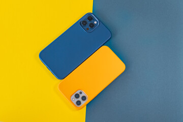 Modern mobile phones in blue and yellow leather cases on a bright background. Modern smartphones with triple lens cameras