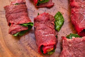 Rolled beef slices on a wooden surface.
