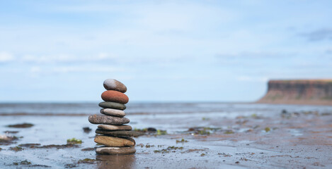 Pebble tower by seaside with blurry mountain background, Stack of Zen rock stones on the sand, Nine Stones pyramid on the beach symbolizing, stability, harmony balance with shallow depth of field.