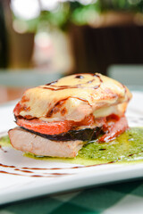 Rosemary chicken with oven-roasted ratatouille served on a white square plate over table with green plaid tablecloth.