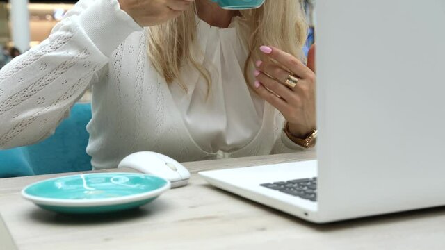 woman with white shirt typing on keyboard pc laptop and cappuccino coffee cup ready standing on light light wooden table
