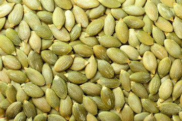 food background of raw pumpkin seeds, top view