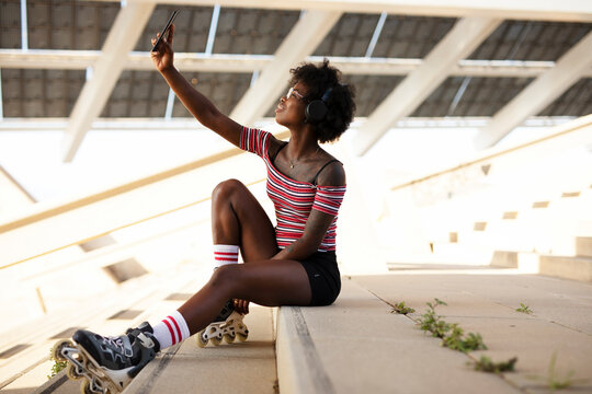 Beautiful African woman with roller skates. Urban sexy girl taking selfie photo