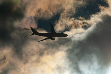 the black silhouette of a passenger airliner against the background of dark sunset clouds