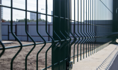 Steel lattice green fence with wire. Fencing. Grid industrial wire fence panels, pvc metal. Installation of sectional fencing. Welded mesh fence. Installation of a grid for fencing the territory.