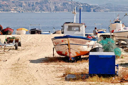 Boats, fishing pot and a fisherman seen from behind on the beach in Soverato (Calabria, Italy)
