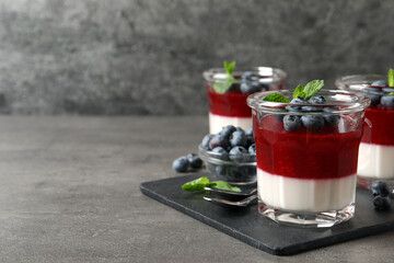 Delicious panna cotta with fruit coulis and fresh blueberries served on grey table. Space for text