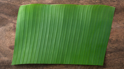 banana leaf on a wooden surface or table top, can be used as a plate, background texture, taken from above with copy space, backdrop for food photography