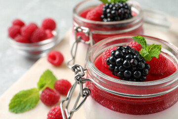 Delicious panna cotta with fruit coulis and fresh berries in glass jars, closeup