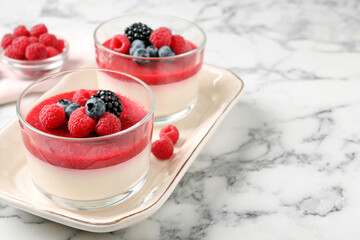 Delicious panna cotta with fruit coulis and fresh berries served on white marble table. Space for...