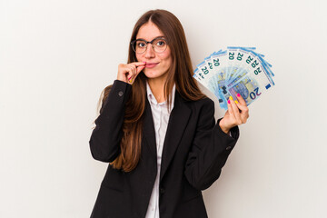 Young caucasian business woman holding banknotes isolated on white background with fingers on lips keeping a secret.