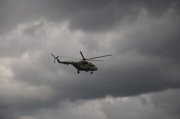 Fototapeta na wymiar A military helicopter in the sky among gray clouds.