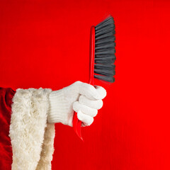 Santa claus holding broom, house or office cleaning concept. red background with copy space.