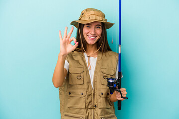 Young caucasian fisherwoman isolated on blue background cheerful and confident showing ok gesture.